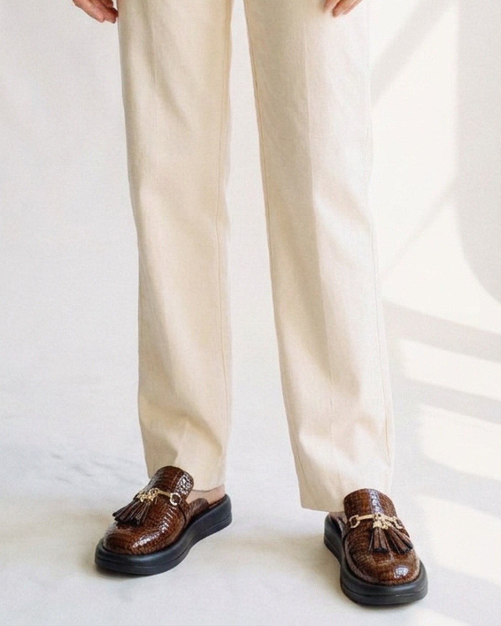 Griselda croc-effect tassel loafer mule, worn on model — lower-body view (AI visualisation)