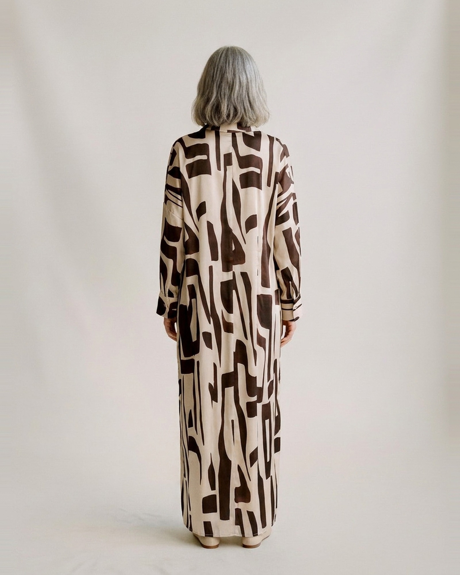 Sandra bruin-creme abstract bedrukte zijdeachtige blousejurk — model-achteraanzicht (AI-visualisatie)