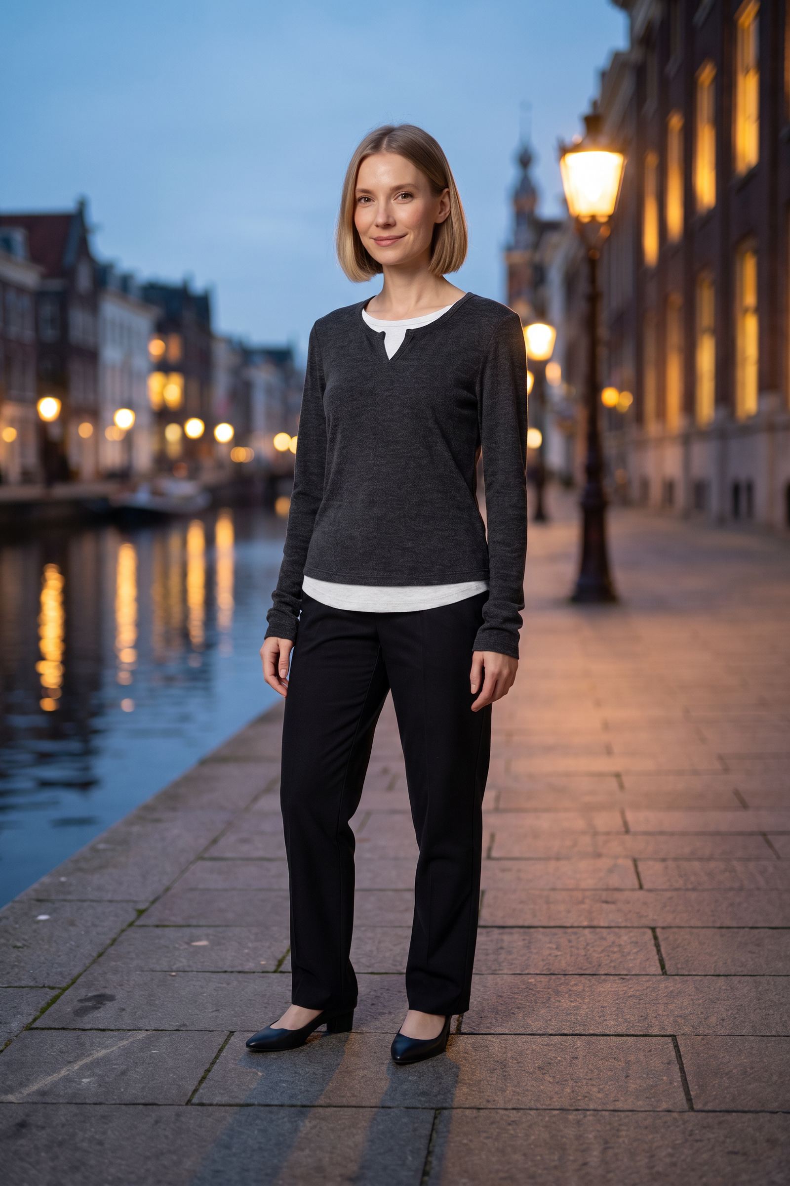 Woman in a charcoal layered-look long-sleeve top by a canal at dusk