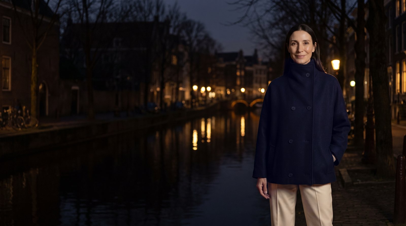 Navy double-breasted wool coat by a canal at night